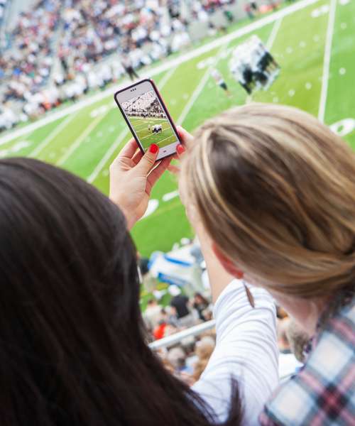 Couple at a sporting event taking picture on mobile